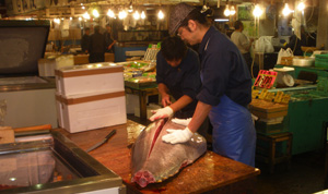 Foto de pescaderos del mercado de Tsukiyi sacando lomos de atún